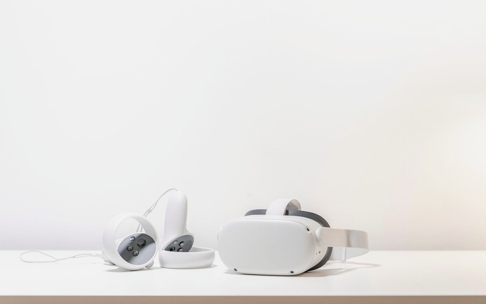 White standalone headset and two ring controllers on a white desk against a plain wall